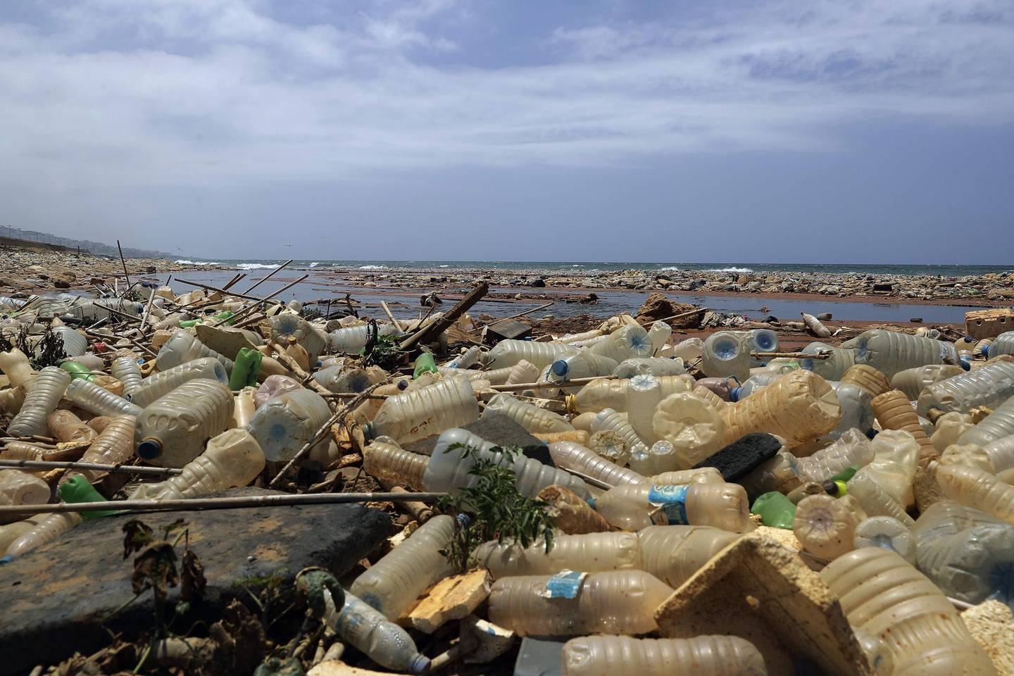 This picture shows a sewage discharge area next to piles of plastic bottles and gallons washed away by the water on the seaside of Ouzai, south of Beirut on July 19, 2018. Many Lebanese nationals are refraining from heading to the beach this summer after reports about high levels of pollution along the country's Mediterranean coast, despite reassurances from government officials that the beaches remain safe.  / AFP / JOSEPH EID
