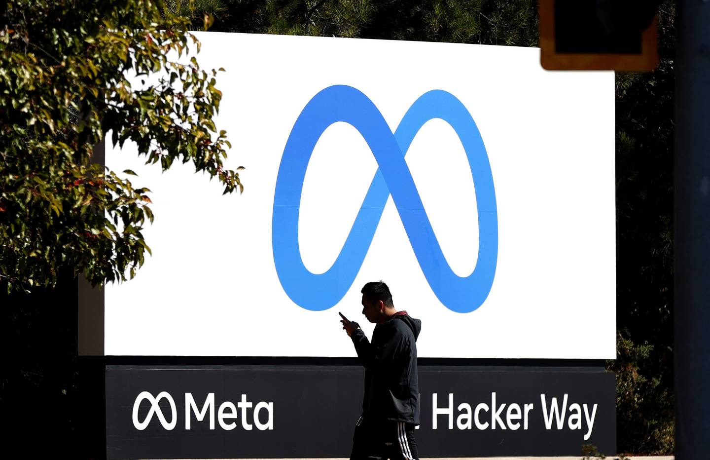 A pedestrian walks in front of a new logo and the name 'Meta' on the sign in front of Facebook headquarters in Menlo Park, California. AFP
