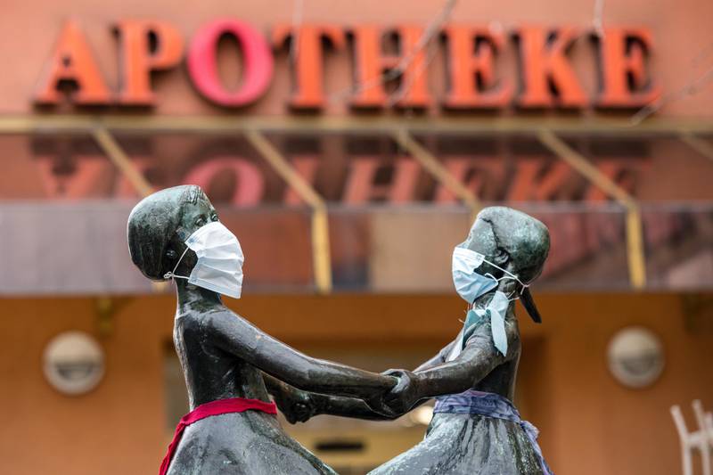The two female heads of a bronze figure wear a protective face mask in Jena, Germany. Getty Images