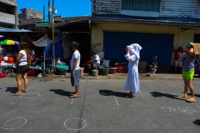 People stand on designated spots to maintain social distancing at a market in Manila.    AFP