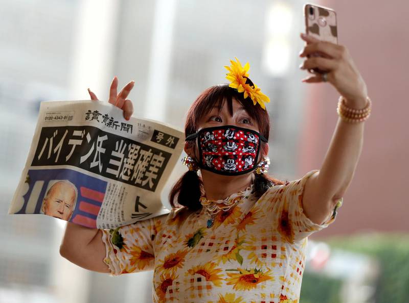 A woman takes selfie photo posing with an extra edition of a newspaper reporting that Democrat Joe Biden is projected to win the 2020 US presidential election, in Tokyo, Japan. Reuters