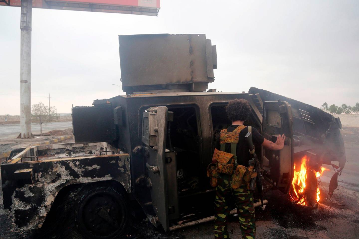 A Huthi rebel inspects a burnt armoured vehicle on September 13, 2018, reportedly destroyed in an air strike during clashes between fighters loyal to Saudi-backed exiled President Abd Rabbo Mansour Hadi and Huthi rebels near the eastern entrance of the Yemeni city of Hodeida, as coalition forces seized rebel supply routes into the coastal city.  Fighting has raged in the last two days close to the rebel-held port city of Hodeida, a crucial entry point for humanitarian aid that the Saudi-led coalition alleges also serves as a key conduit for arms to the Iran-backed Huthis.  / AFP / STRINGER
