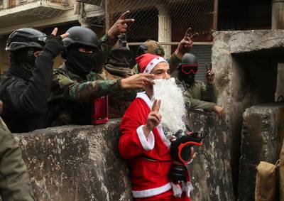 Iraqi security forces take pictures with a protester dressed as Santa Claus during ongoing protests on Rasheed Street in Baghdad. AP Photo