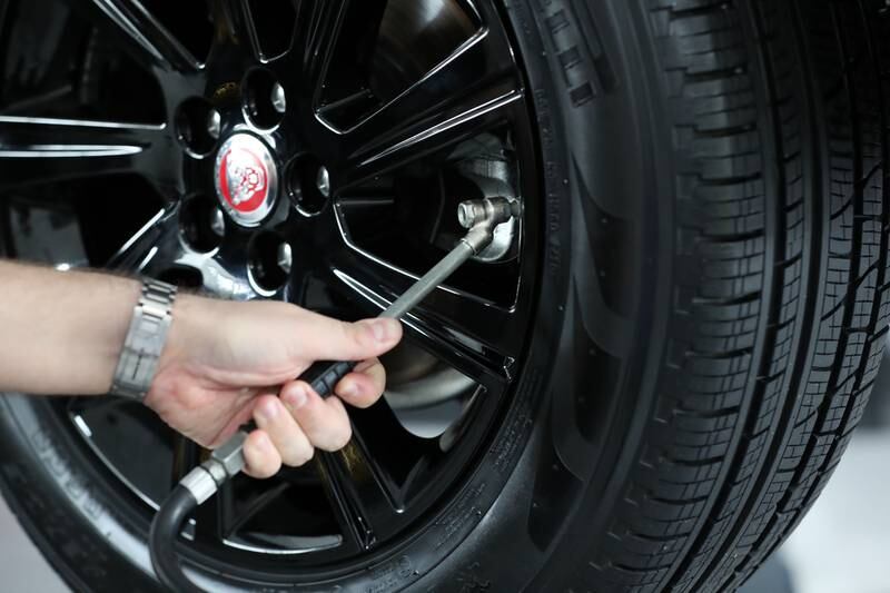 Ryan Hughes checks the tyre pressure of a car. Chris Whiteoak/ The National