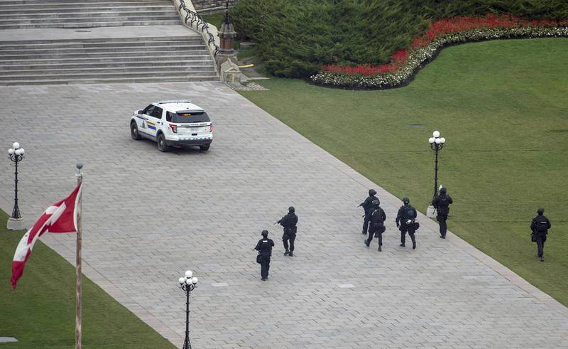 Police teams move towards the centre block in their hunt for possible gunmen. Justin Tang, The Canadian Press