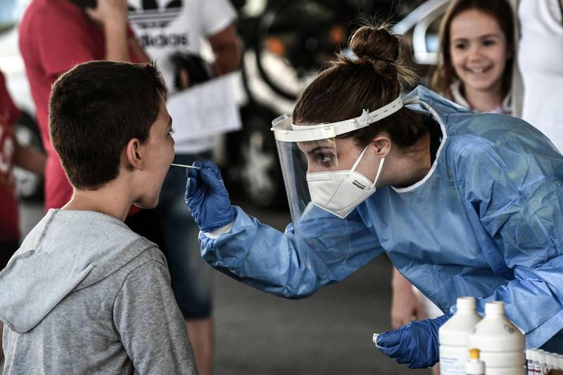 A health worker collects a swab sample from a boy to test for COVID-19 at the Greek-Bulgarian border crossing in Promachonas. AFP