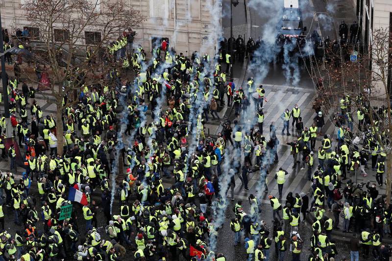 Tear gas floats in the air around protesters wearing yellow vests during clashes with French Gendarmes on the Champs-Elysees Avenue as part of a demonstration by the 'yellow vests' movement in Paris, France, December 8, 2018. Reuters