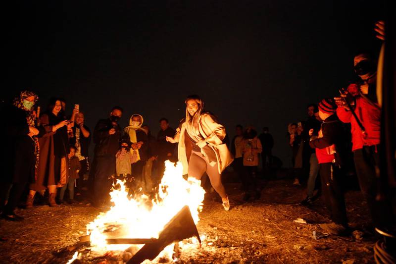 A girl prepares to jump over a fire, as onlookers watch, during Charshanbeh Suri celebrations in Tehran. EPA