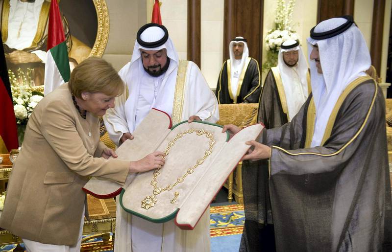 German Chancellor Angela Merkel is given the Sheikh-Zaid-Order by Sheikh Khalifa bin Zayed Al Nahyan (C), President of the United Arab Emirates, on May 25, 2010 in Abu Dhabi. Merkel arrived in Abu Dhabi on May 24 for the first leg of a four-nation Gulf tour and promptly signed a series of accords, including on hydrocarbon sector cooperation.    AFP PHOTO     HO BUNDESREGIERUNG/GUIDO BERGMANN    GETTY OUT / AFP PHOTO / HO BUNDESREGIERUNG / GUIDO BERGMANN