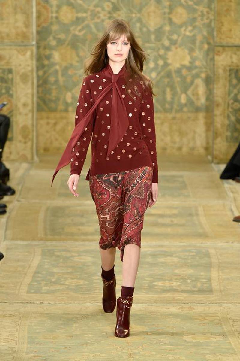 Modern Bohemia at Tory Burch. “Marrakech meets Chelsea” was Tory Burch’s catalyst for autumn/winter 2015. Walls, floors and seats of the elaborate space where the early morning show was held were covered in matching, antique rugs. Burch reinterpreted the geometric shapes of the Moroccan carpets into her pieces — small sections of the rugs were blown up and placed on skirts and entire prints were mirrored onto dresses, bags and heavy wool coats. Pale blues and greys moulded into violets and brick red. Waists were dropped to hip level and loosely tied with fringed belts. Jumpers dusted with gold sequins evoked the shadows created by tin punch lanterns on carmine ceilings. An overall feeling of free-spirited ease was palpable. Slaven Vlasic / Getty Images for Tory Burch / AFP
