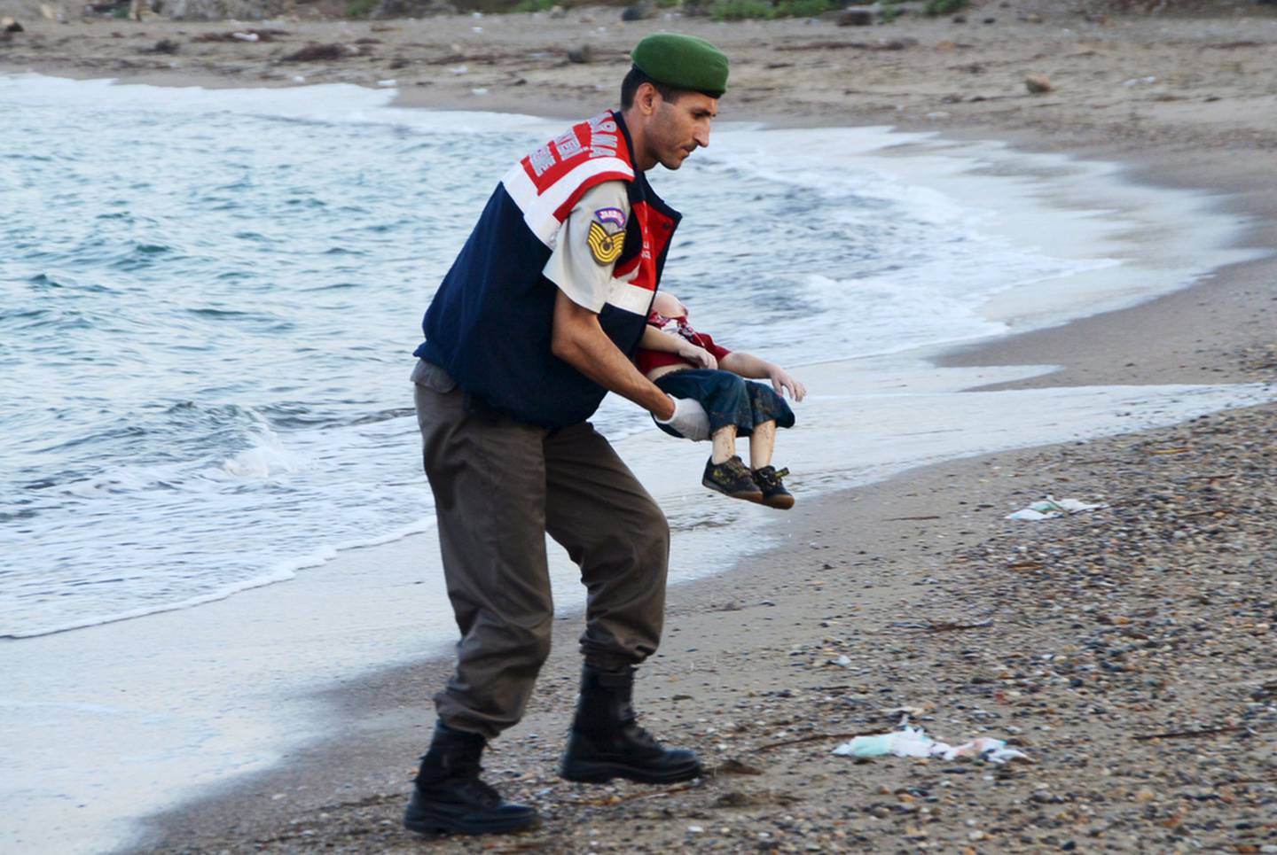 A Turkish gendarme retrieves the body of Syrian refugee Alan Kurdi from a beach in Turkey. Reuters
