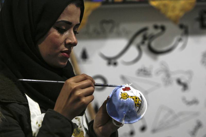 Palestinian artist Samah Said paints a dust mask for a project raising awareness about the COVID-19 coronavirus pandemic, in Gaza City.   AFP
