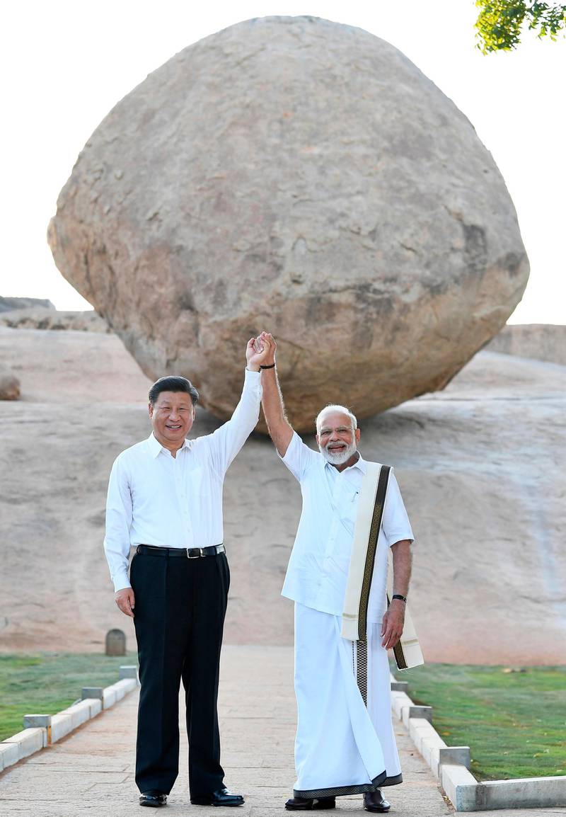 The Indian and Chinese leaders raise hands at Arjuna's Penance in Mamallapuram. AP