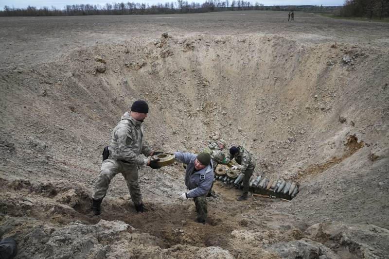 Ukrainian interior ministry soldiers collect explosives in a hole to detonate them near a minefield after battles with Russia at the village of Moshchun close to Kyiv. AP