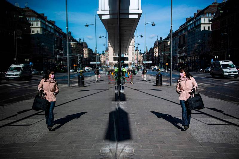 A woman wearing a protective face mask checks her reflection on a window in Stockholm, Sweden, on April 2, 2020. AFP