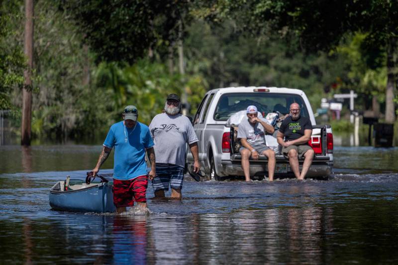 A man tows a canoe through a flooded street in New Smyrna Beach, Florida. AFP