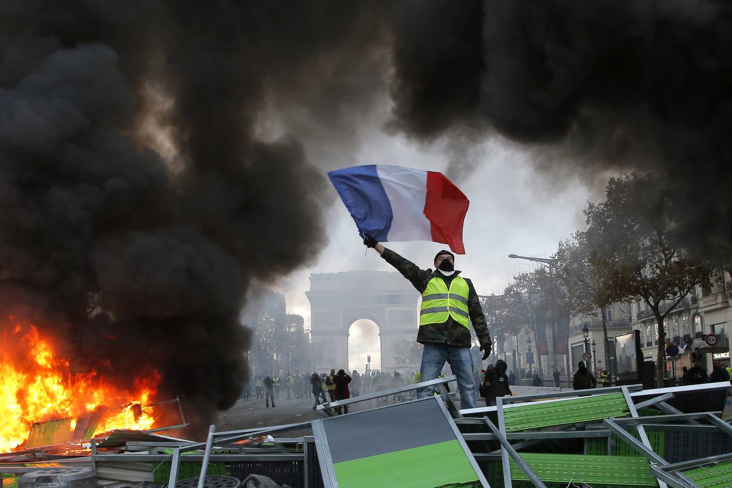 A demonstrator waves the French flag on a burning barricade on the Champs-Elysees in Paris, during a Yellow Vest demonstration in 2018. AP Photo