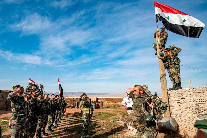 Syrian government soldiers perform a salute as others raise up a government national flag upon a wooden pole as they deploy for the first time in the eastern countryside of the city of Qamishli in the northeastern Hasakah province. AFP