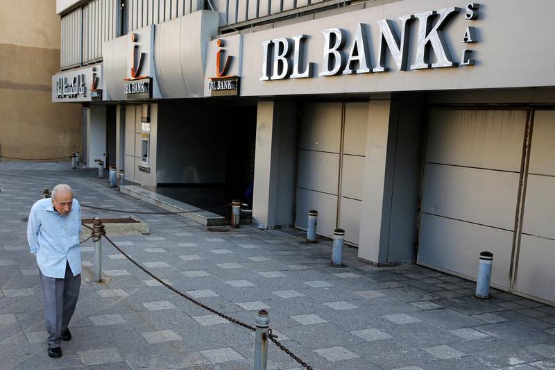 A man passes by a closed bank in Beirut, Lebanon, Tuesday, Nov. 12, 2019. Lebanon's banking association says banks will stay closed due to a strike by employees, as country's financial crisis worsens. (AP Photo/Bilal Hussein)