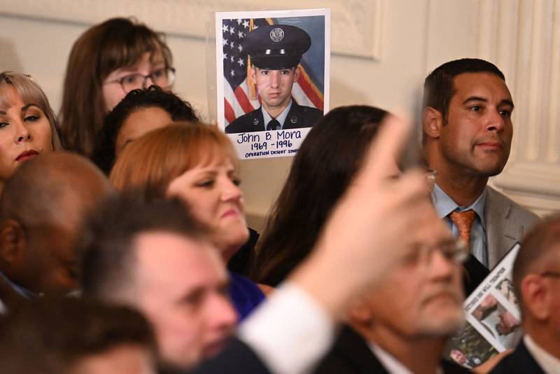 An attendee holds up a photo of deceased US veteran John Mora during the signing ceremony. AFP