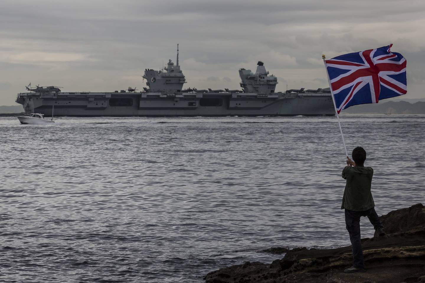 A man waves a British national flag as the British Royal Navy aircraft carrier HMS Queen Elizabeth sails out of Tokyo bay in September. Getty Images
