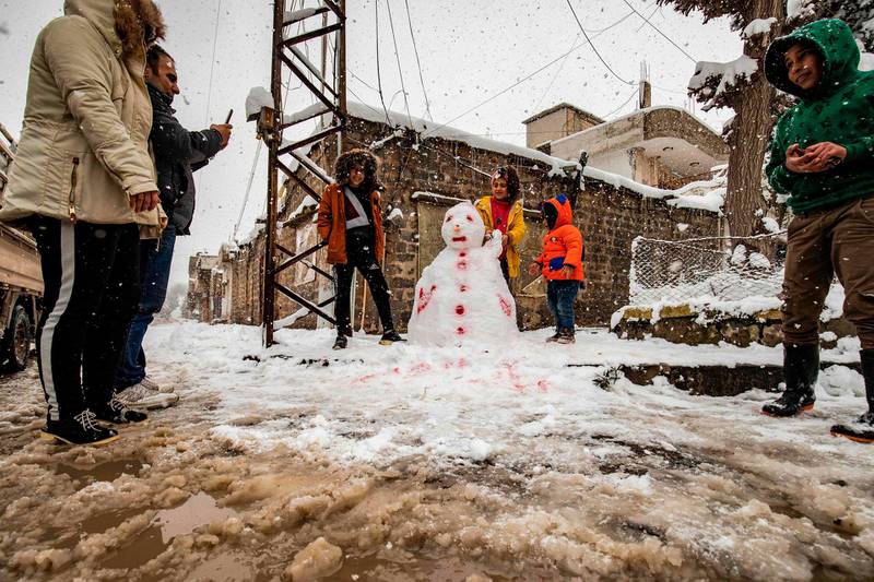 Children build a snowman together in the northeastern Syrian town of al-Malikiyah (Derik) at the border with Turkey after a blizzard.   AFP