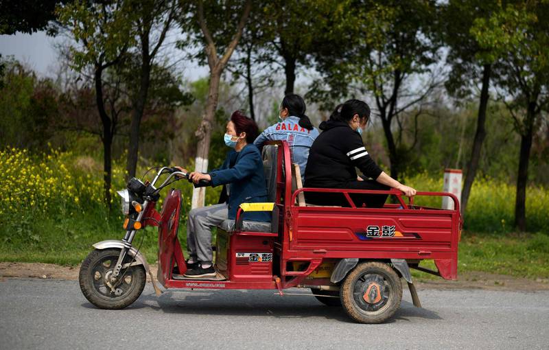 People wearing face masks ride on a motorised tricycle along a street in Huanggang, in China’s central Hubei province. AFP