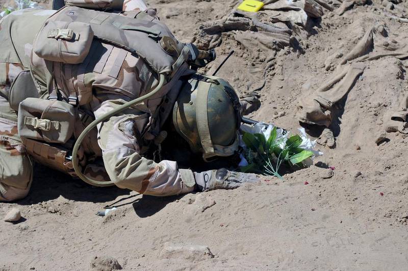 A soldier prays at a mass grave for Shiite soldiers killed at Camp Speicher. Reuters
