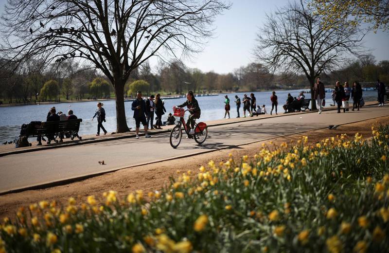 A person cycles through Hyde Park in sunny weather in London. Reuters