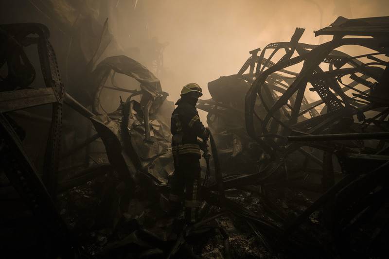 A Ukrainian firefighter drags a hose inside a large food products storage facility which was destroyed by an air strike on the outskirts of Kyiv. AP