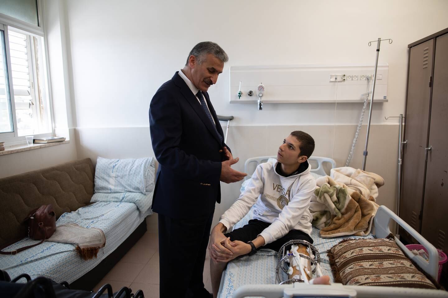 Dr Hussam Abu Saa, head of the orthopaedic department, speaks with a young patient. Corinna Kern for The National