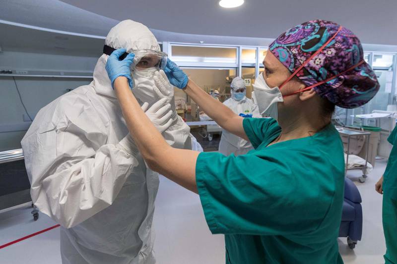 epa08383792 A nurse helps a colleague to wear personal protective equipment (PPE) at the Intensive Care Unit (ICU) of Morales Meseguer Hospital in Murcia, Spain, 25 April 2020, during the coronavirus disease (COVID-19) pandemic. According to health workers at the Morales Meseguer ICU, one of the hardest parts to deal with during the coronavirus crisis has been not being able to hold the hand of the dying persons as there was a high risk of contagion.  EPA/MARCIAL GUILLEN