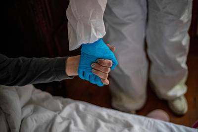 A healthcare worker holds the hand of a homeless woman in a hotel in Prague, Czech Republic. EPA