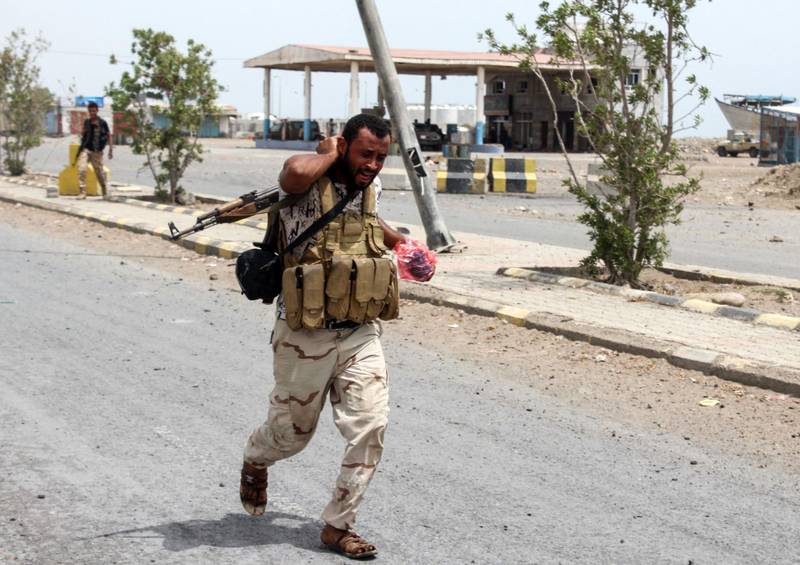 A Yemeni fighter from the Amalqa ("Giants") Brigades, loyal to the Saudi-backed government, walks carrying a package along a road during the offensive to seize the Red Sea port city of Hodeidah from Iran-backed Houthi rebels, on its southern outskirts near the airport on June 21, 2018. Saleh Al-Obeidi / AFP