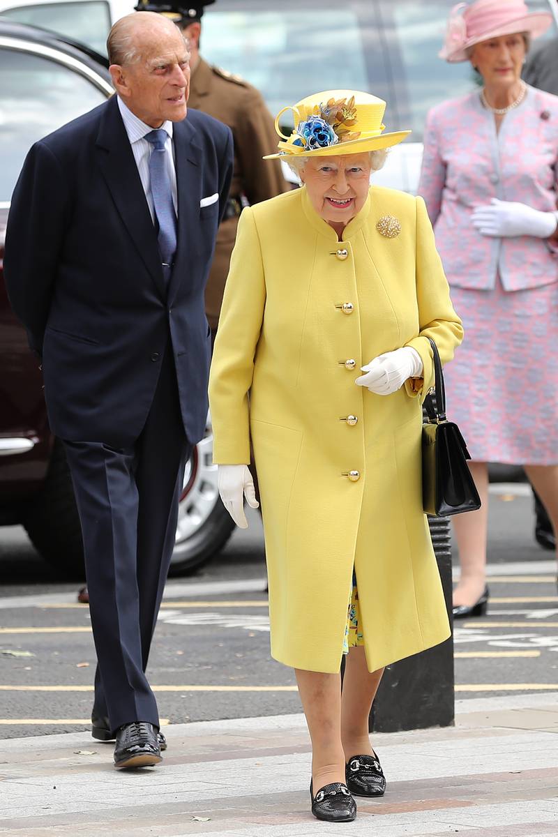 Queen Elizabeth II, wearing yellow, and Prince Philip, Duke of Edinburgh, arrive at New Scotland Yard on July 13, 2017, in London. Getty Images