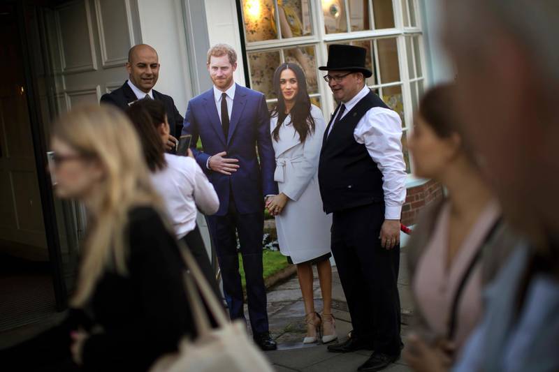 People pose for photos next to cut-out figures of Britain's Prince Harry and Meghan Markle. Emilio Morenatti / AP Photo