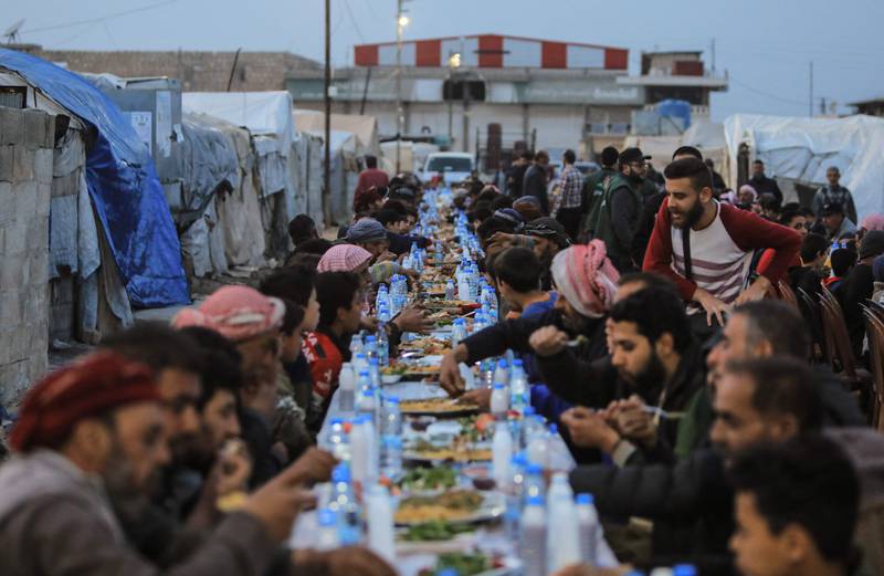 Displaced Syrians share an iftar meal, donated by relief organisation ULFAH with support from Malaysia, near Al Bab in Aleppo province. AFP