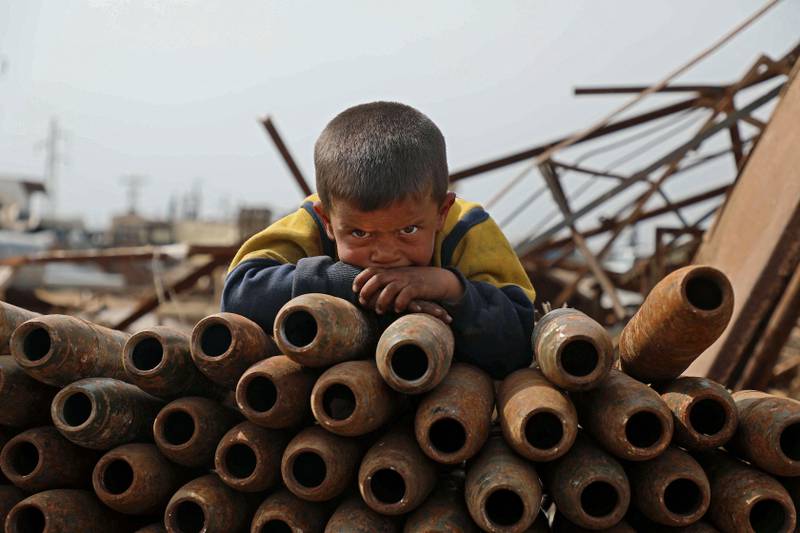 A Syrian child rests on a stack of neutralised shells at a metal scrapyard on the outskirts of Maaret Misrin town, in Idlib province, on March 10. A family displaced from the village of Latamneh in Hama's northern countryside four years ago, has found a source of income in collecting and selling metal scrap, including unexploded ordnance shells. AFP
