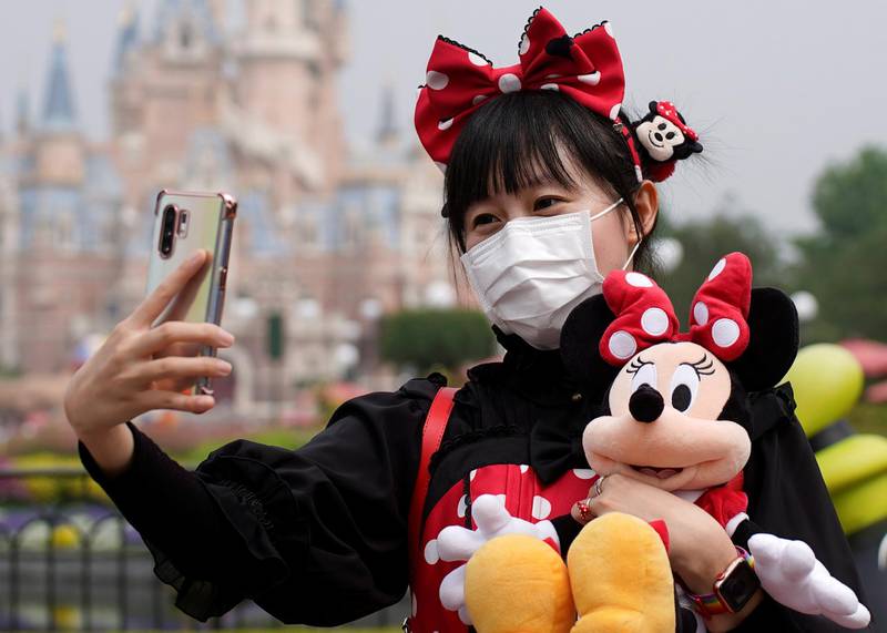 A visitor dressed as a Disney character takes a selfie while wearing a protective face mask as the Shanghai Disneyland theme park reopens following a shutdown after the coronavirus outbreak, in Shanghai, China, on May 11, 2020. Reuters