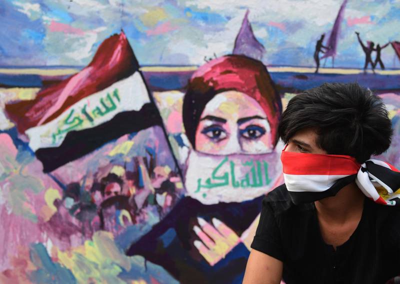 An Iraqi protester sits next to a wall painted with a graffiti near the Al Tahrir square in central Baghdad.  EPA