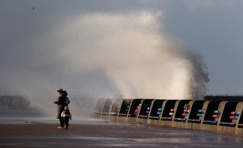 Waves break over the sea wall in strong winds at New Brighton. Reuters
