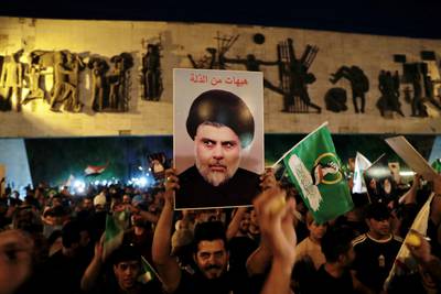 Followers of Shiite cleric Muqtada al-Sadr celebrate holding his poster, after the announcement of the results of the parliamentary elections in Tahrir Square, Baghdad, Iraq, on Monday, October 11, 2021. AP