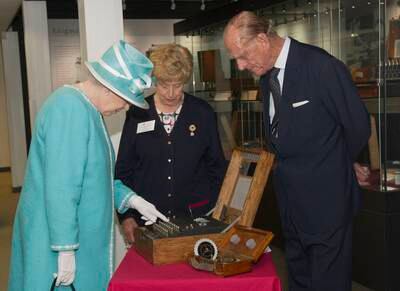 Queen Elizabeth II presses the button to start the enigma codebreaking machine as Prince Philip, Duke of Edinburgh, and wartime operator Ruth Bourne look on during a visit to Bletchley Park in 2011