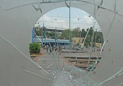 Railway Protection Force personnel walk across tracks as seen from a broken glass window a day after the demonstrations. 