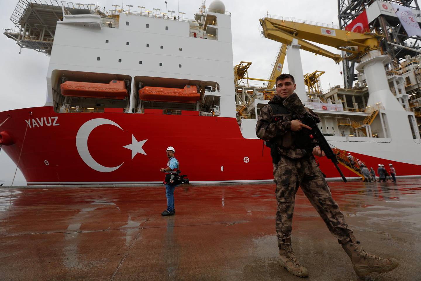 FILE - In this Thursday, June 20, 2019 file photo, a Turkish police officer patrols the dock, backdropped by the drilling ship 'Yavuz' to be dispatched to the Mediterranean, at the port of Dilovasi, outside Istanbul.  The leaders of Greece, Israel and Cyprus are set to sign a deal Thursday Jan. 2, 2020, for a 1,900-kilometer (1,300-mile) undersea pipeline that will carry gas from new offshore deposits in the southeastern Mediterranean to continental Europe. (AP Photo/Lefteris Pitarakis, File)