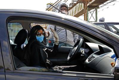 A member of Iranian Red Crescent tests people with possible coronavirus Covid-19 symptoms, as police blocked Tehran to Alborz highway. AFP