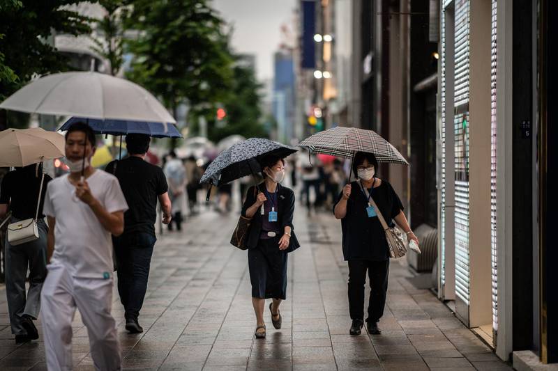 TOKYO, JAPAN - JUNE 30: People wearing face masks shelter from the rain under umbrellas as they walk along a street on June 30, 2020 in Tokyo, Japan. Tokyo confirmed 54 new Covid-19 coronavirus infections today, the fifth consecutive day with more than 50 cases. Yokohama also recorded its highest daily figure since April 23rd. Nevertheless, Tokyos Governor, Yuriko Koike, stated recently that the increase does not indicate the arrival of a second wave. Japan has so far recorded 18,477 infections, 972 deaths and 16,392 recoveries from the virus. (Photo by Carl Court/Getty Images)