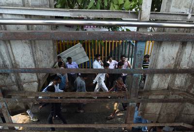 Indian pedestrians walk through the scene of a stampede on a railway bridge in Mumbai. Punit Paranjpe / AFP