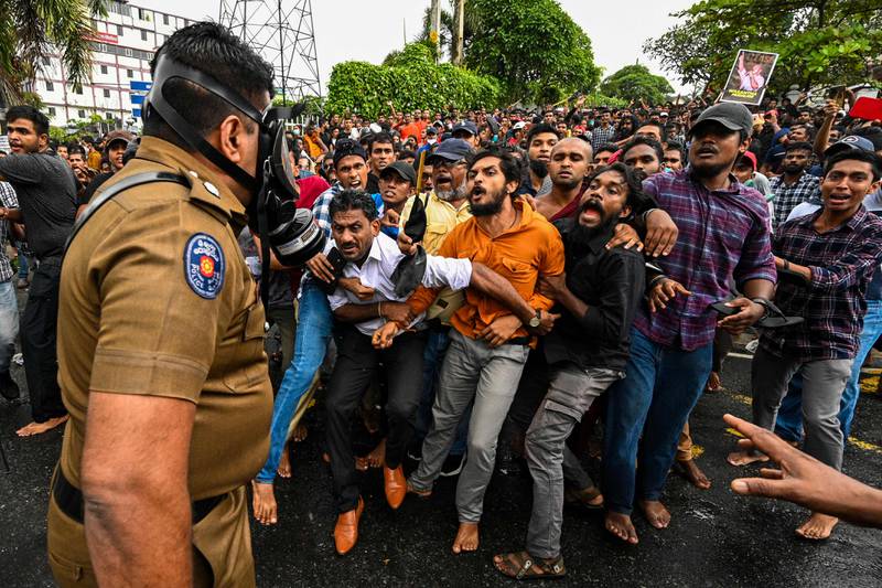 A Sri Lankan policeman confronts protesters taking part in an anti-government demonstration by university students demanding the release of their leaders, in Colombo. AFP