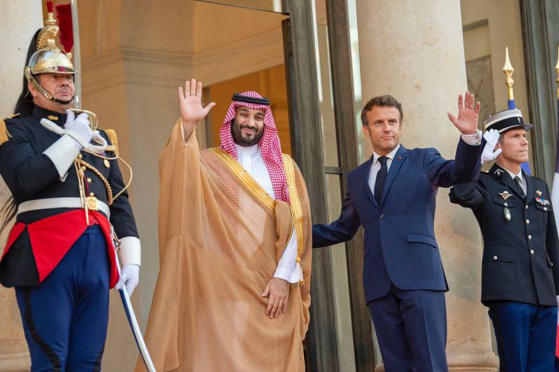Mr Macron and Prince Mohammed wave to the media. 